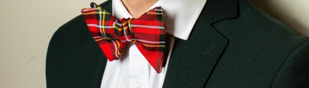 nœud papillon en tartan rouge porté sur veste verte